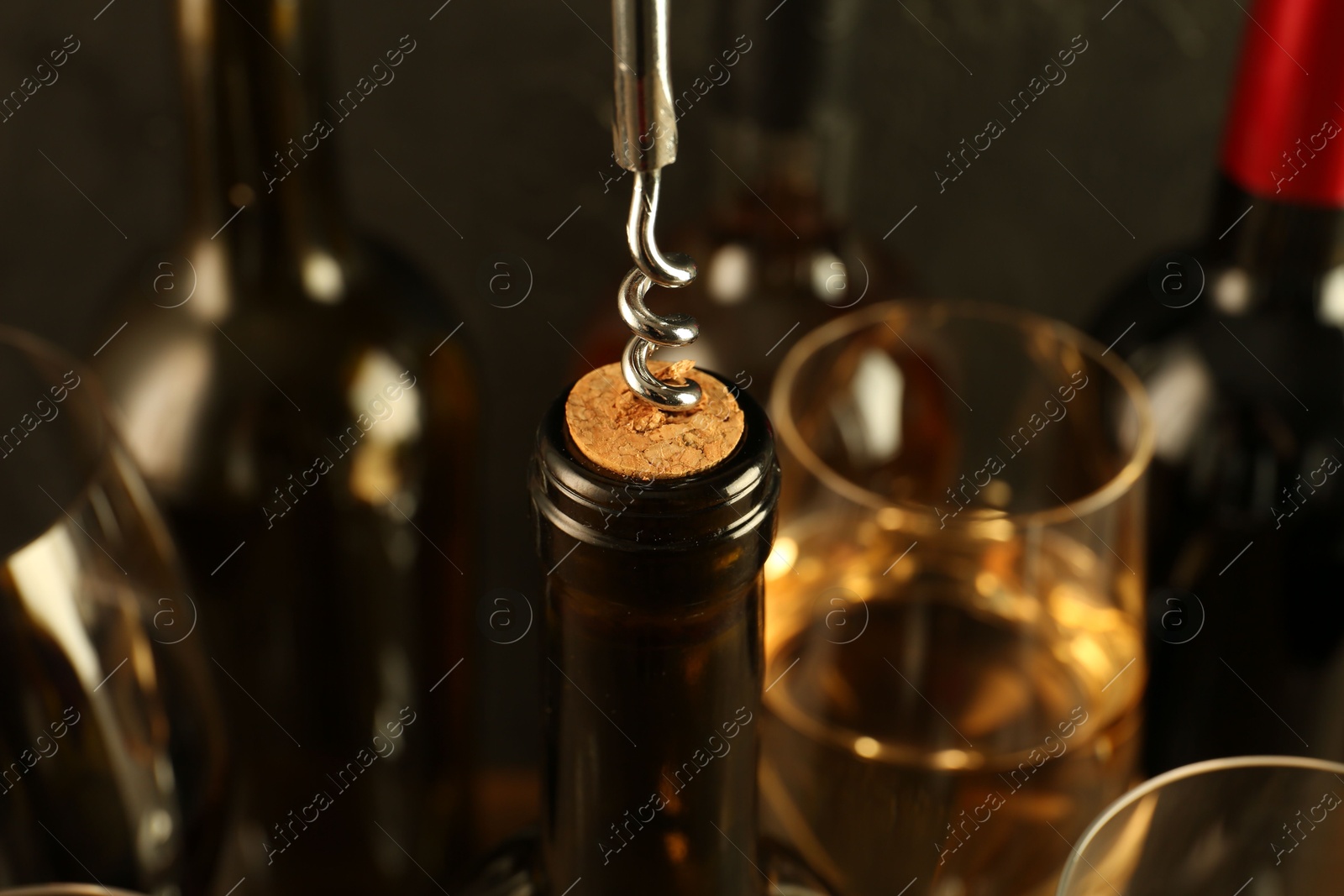 Photo of Wine bottle with corkscrew on blurred background, closeup