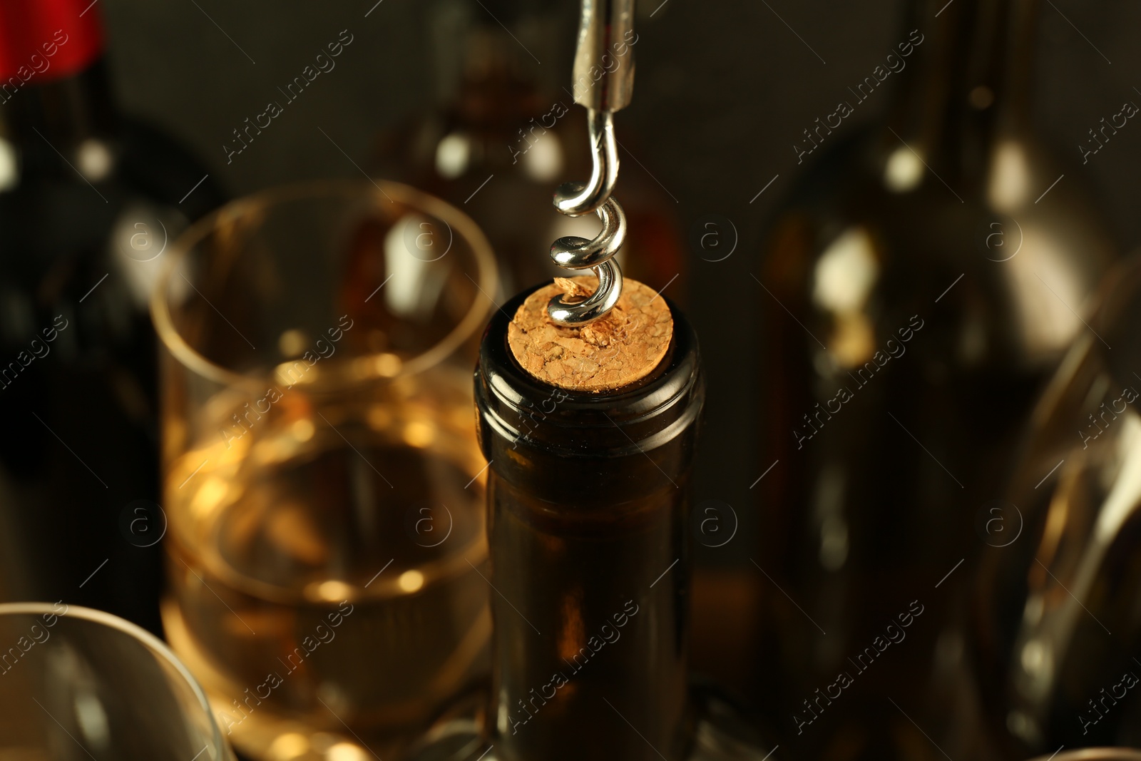 Photo of Wine bottle with corkscrew on blurred background, closeup