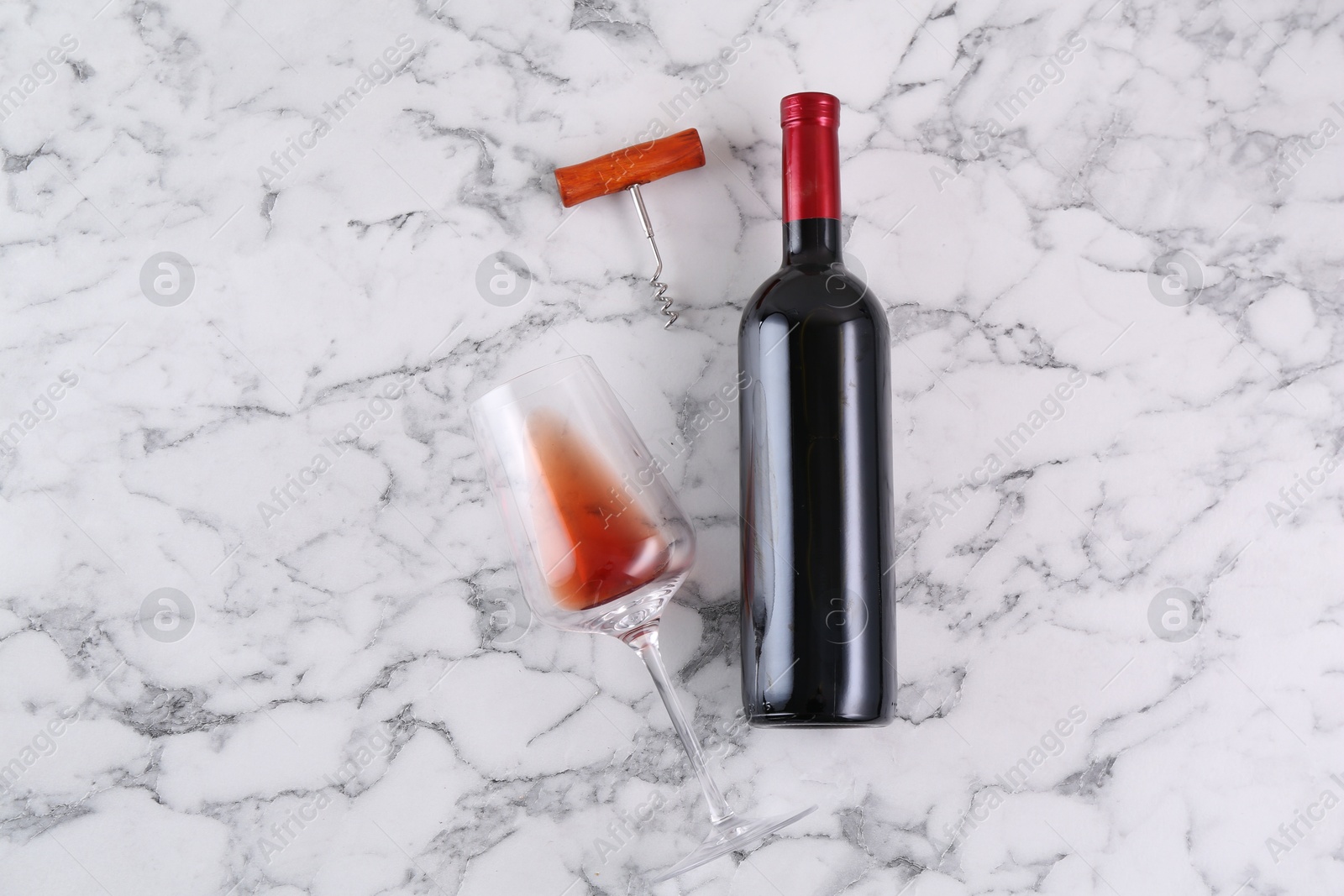 Photo of Corkscrew, bottle of wine and glass on white marble table, flat lay