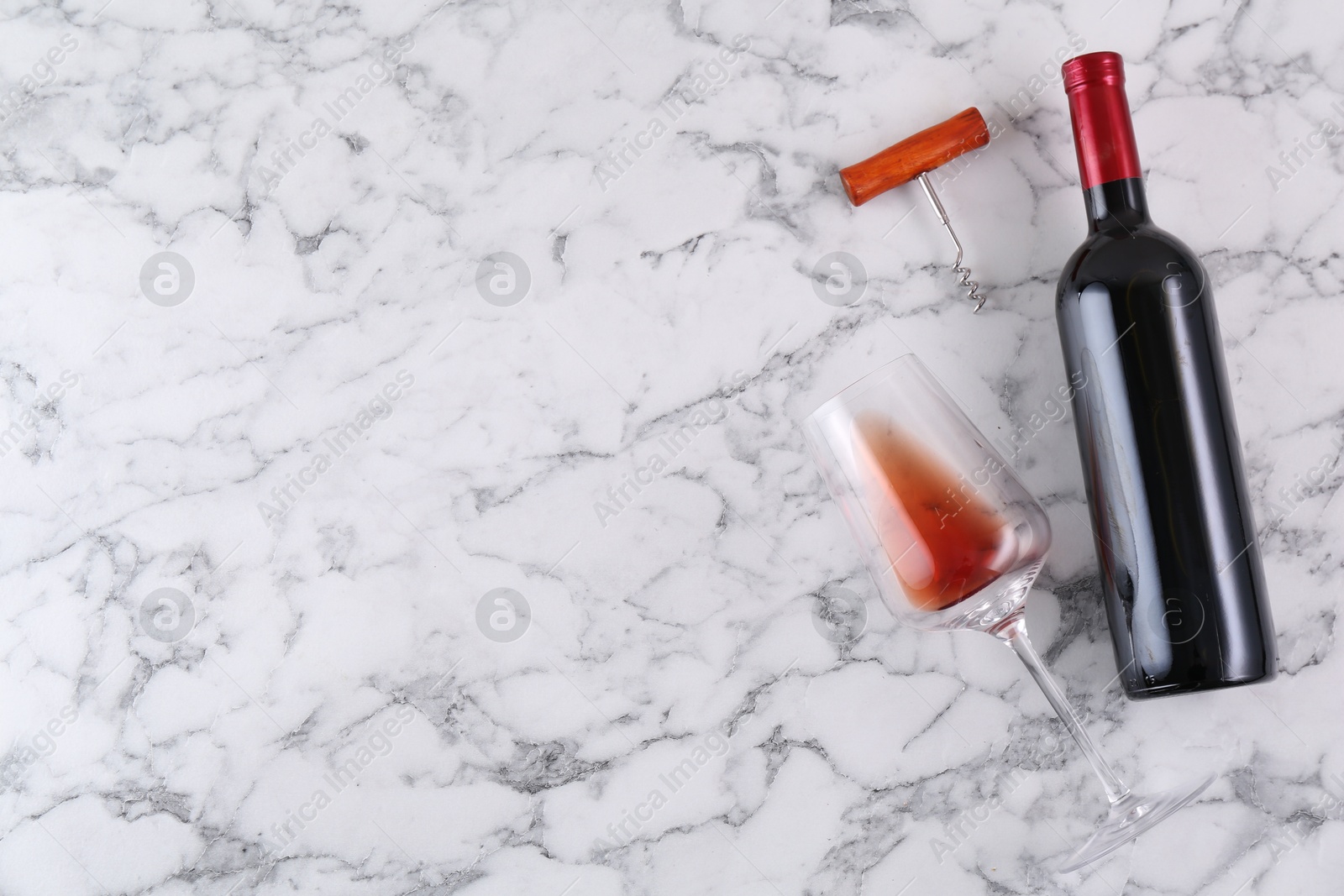 Photo of Corkscrew, bottle of wine and glass on white marble table, flat lay. Space for text