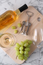 Wing corkscrew, bottle of wine, glasses, walnuts and grapes on white marble table, top view