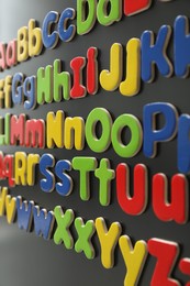 Photo of Alphabetical order. Many bright magnetic letters on fridge indoors, closeup