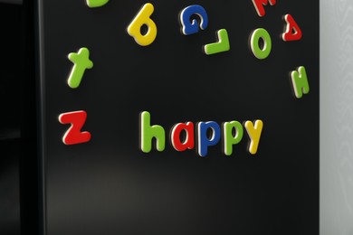 Word Happy made of many bright magnetic letters on fridge indoors. Learning alphabet