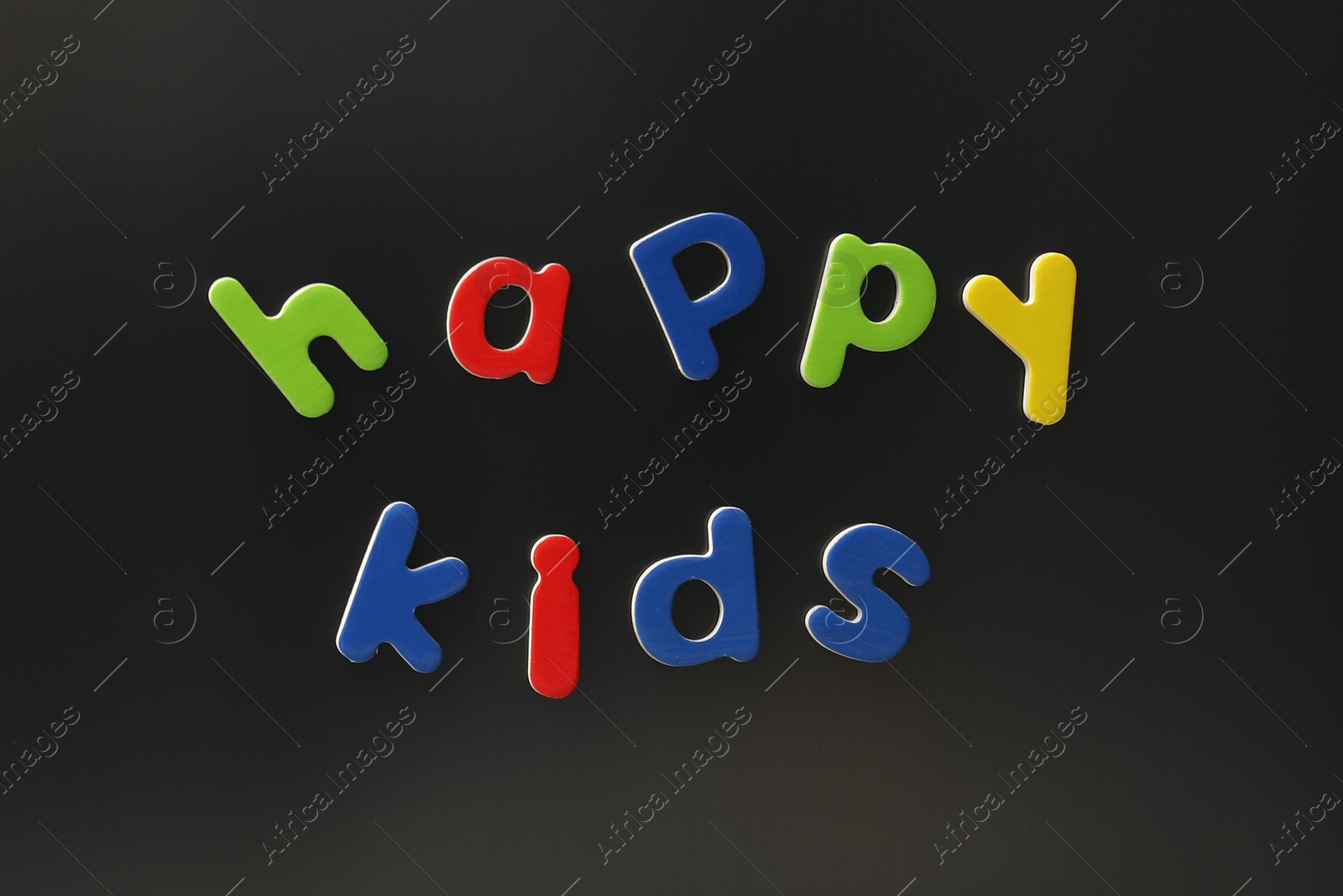 Photo of Words Happy Kids made of bright magnetic letters on fridge. Learning alphabet