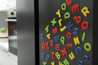 Many bright magnetic letters on fridge indoors. Learning alphabet