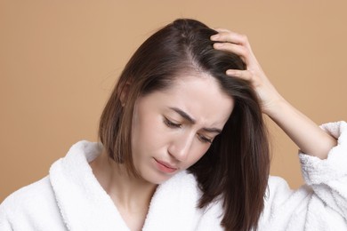 Sad woman with hair loss problem on light brown background