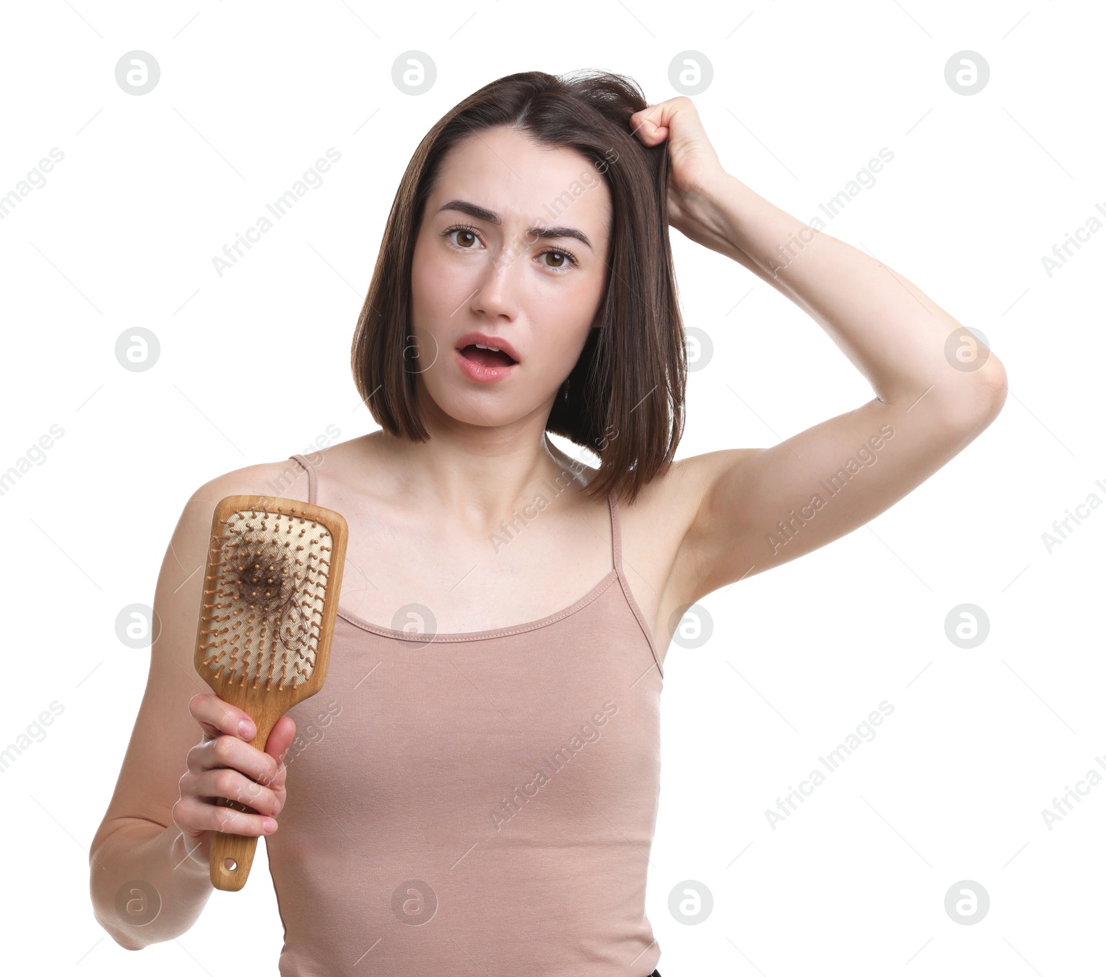 Photo of Emotional woman holding brush with lost hair on white background. Alopecia problem