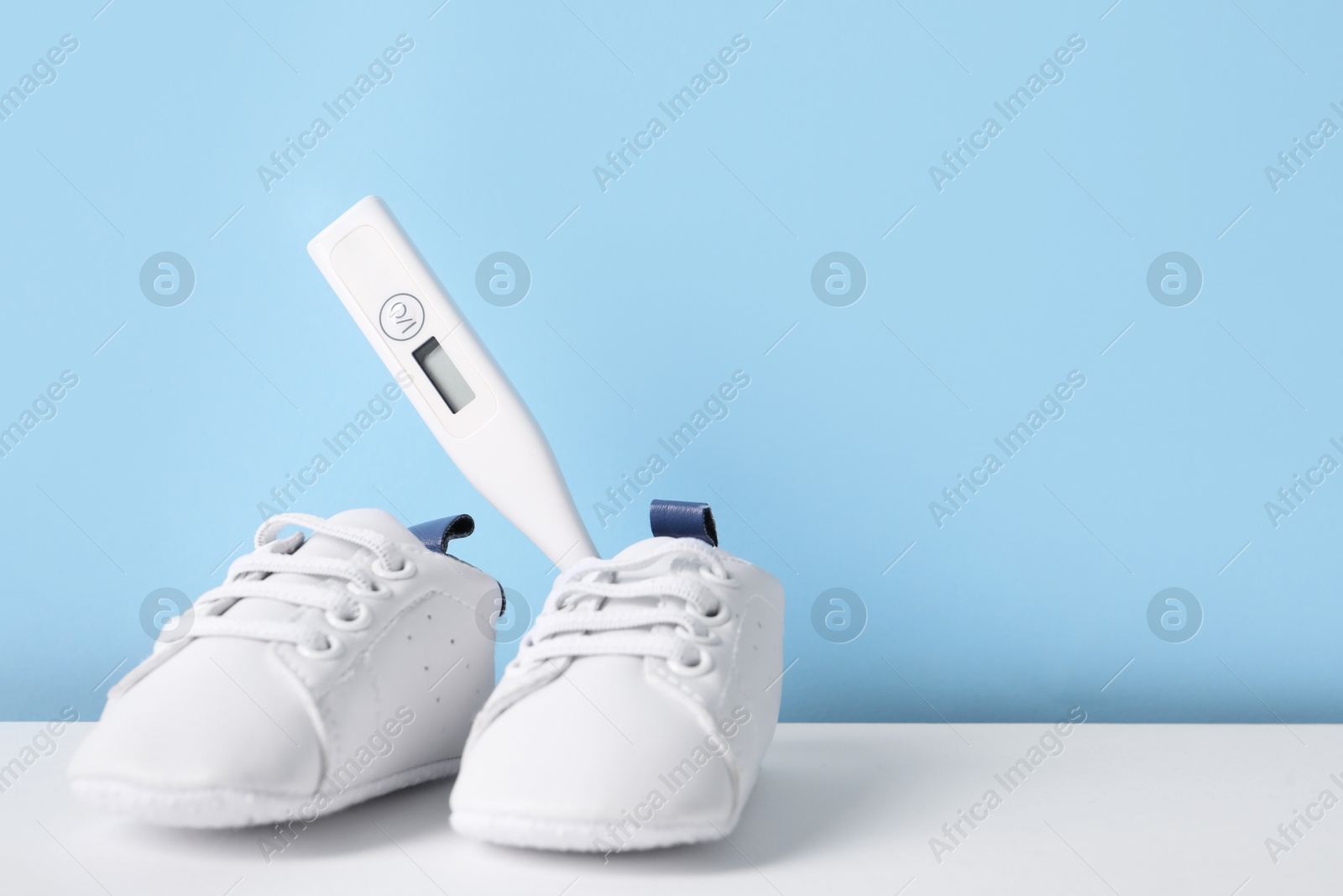 Photo of Child`s sneakers and thermometer on color background, space for text
