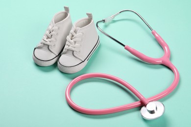 Stethoscope and kid's sneakers on turquoise background