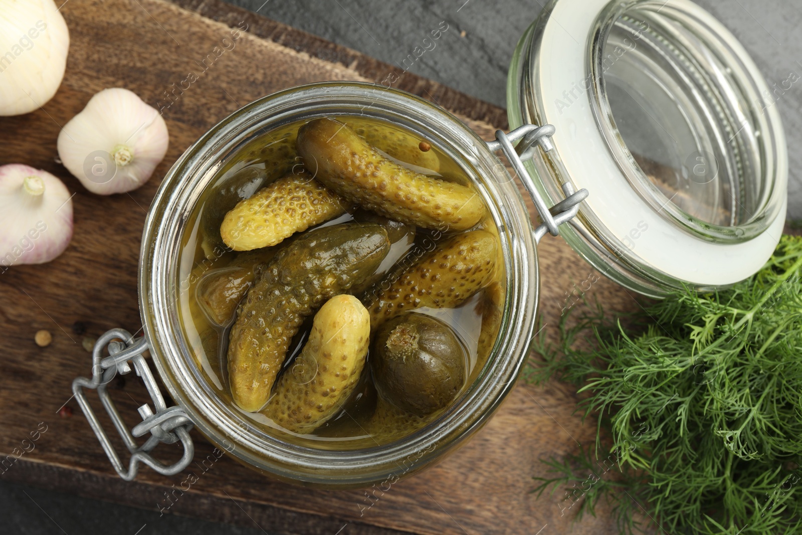 Photo of Pickled cucumbers in jar, dill and garlic on grey table, flat lay