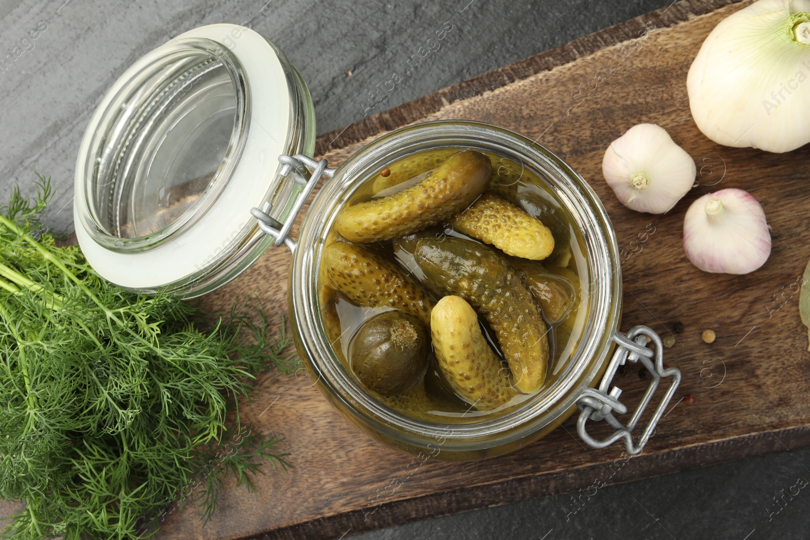 Photo of Pickled cucumbers in jar, dill and garlic on grey table, flat lay