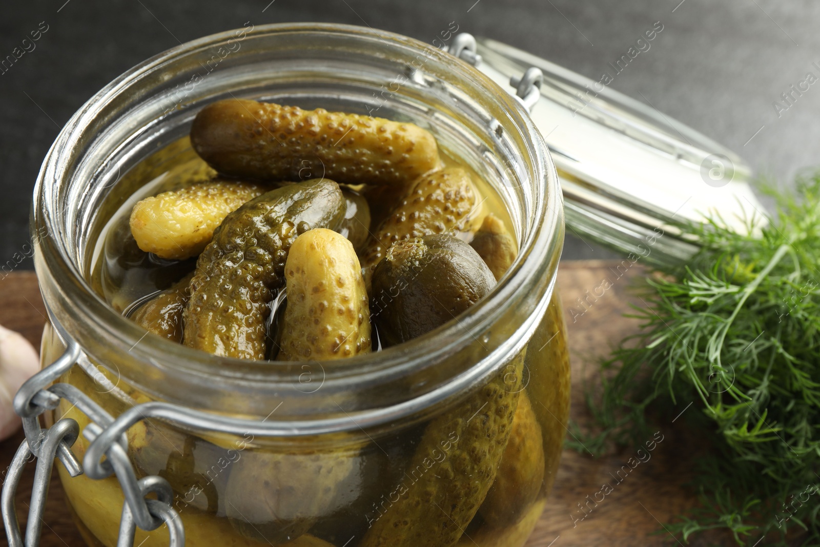 Photo of Pickled cucumbers in jar and dill on grey table, closeup