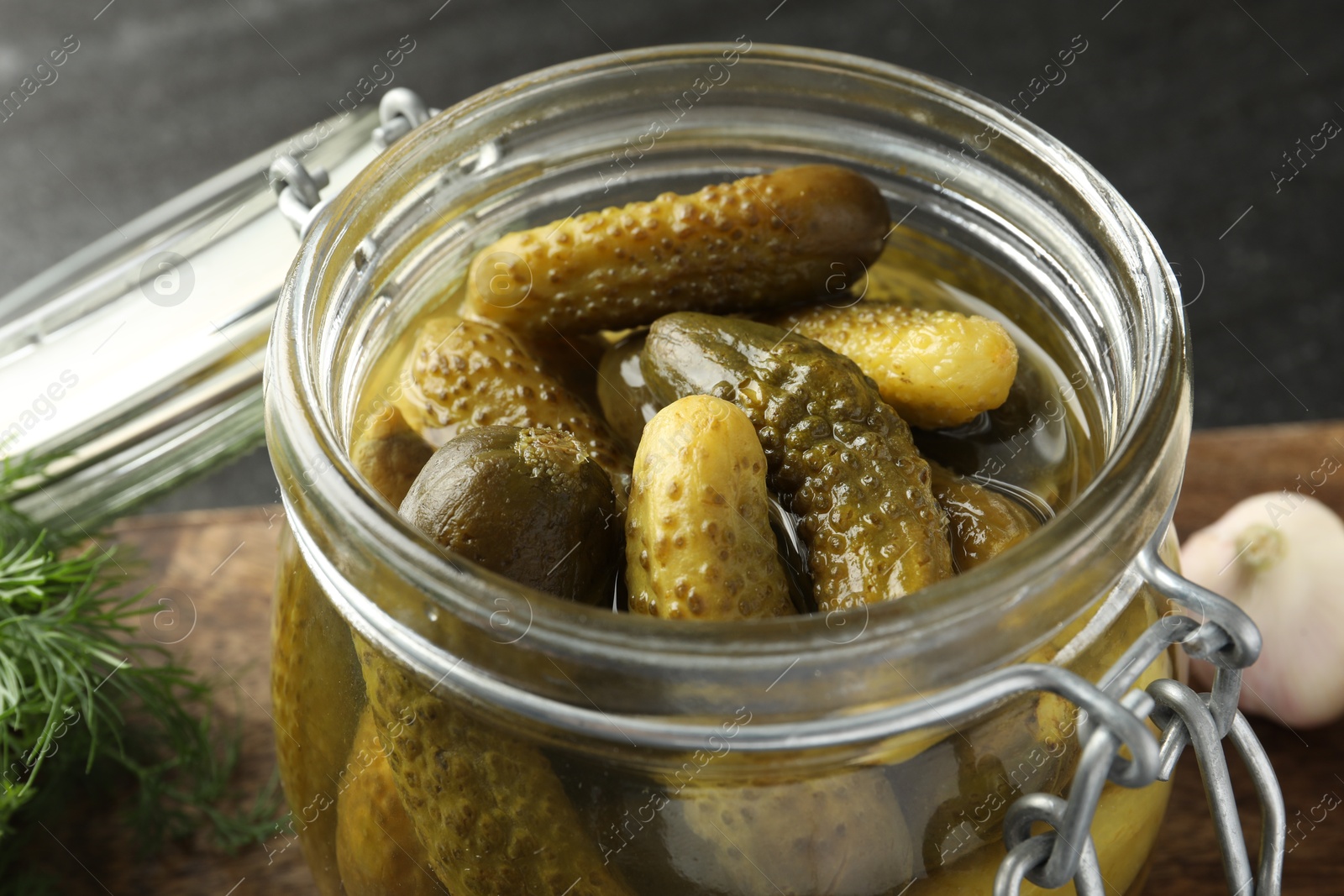 Photo of Pickled cucumbers in jar on grey table, closeup