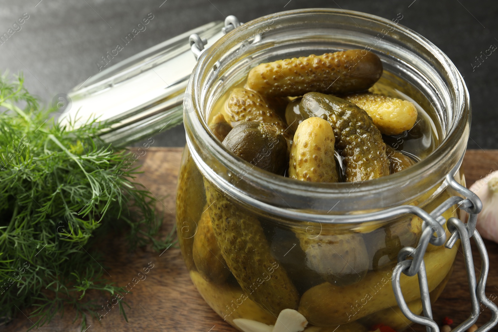 Photo of Pickled cucumbers in jar and dill on grey table, closeup