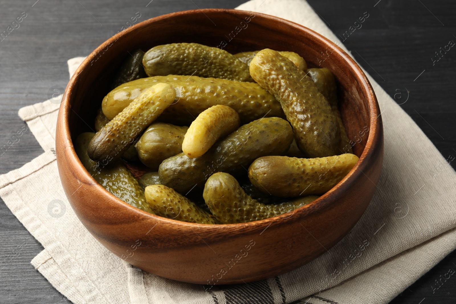 Photo of Pickled cucumbers in bowl on grey wooden table, closeup