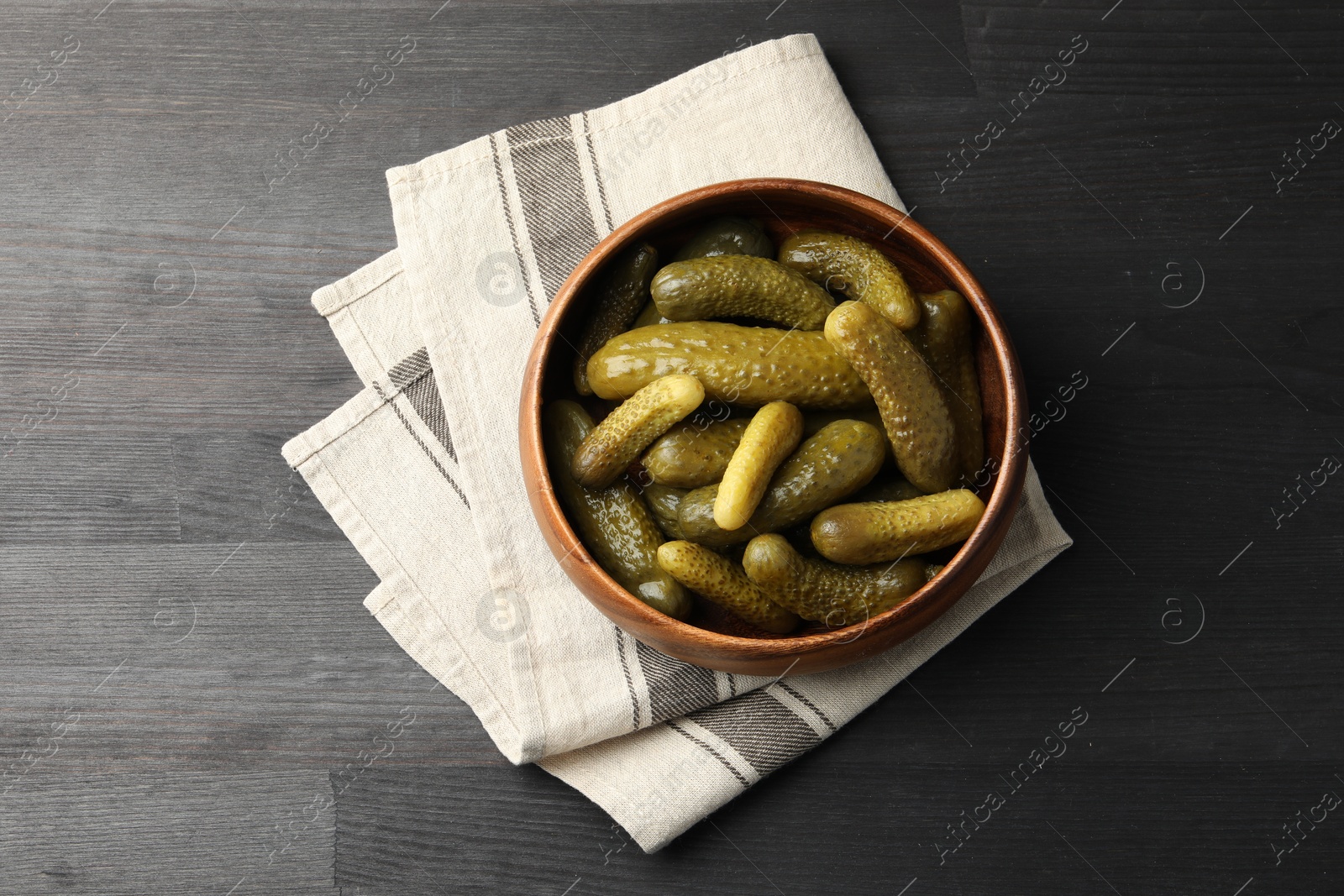 Photo of Pickled cucumbers in bowl on grey wooden table, top view