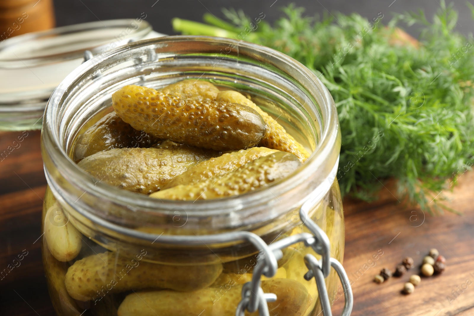 Photo of Pickled cucumbers in jar and dill on wooden table, closeup