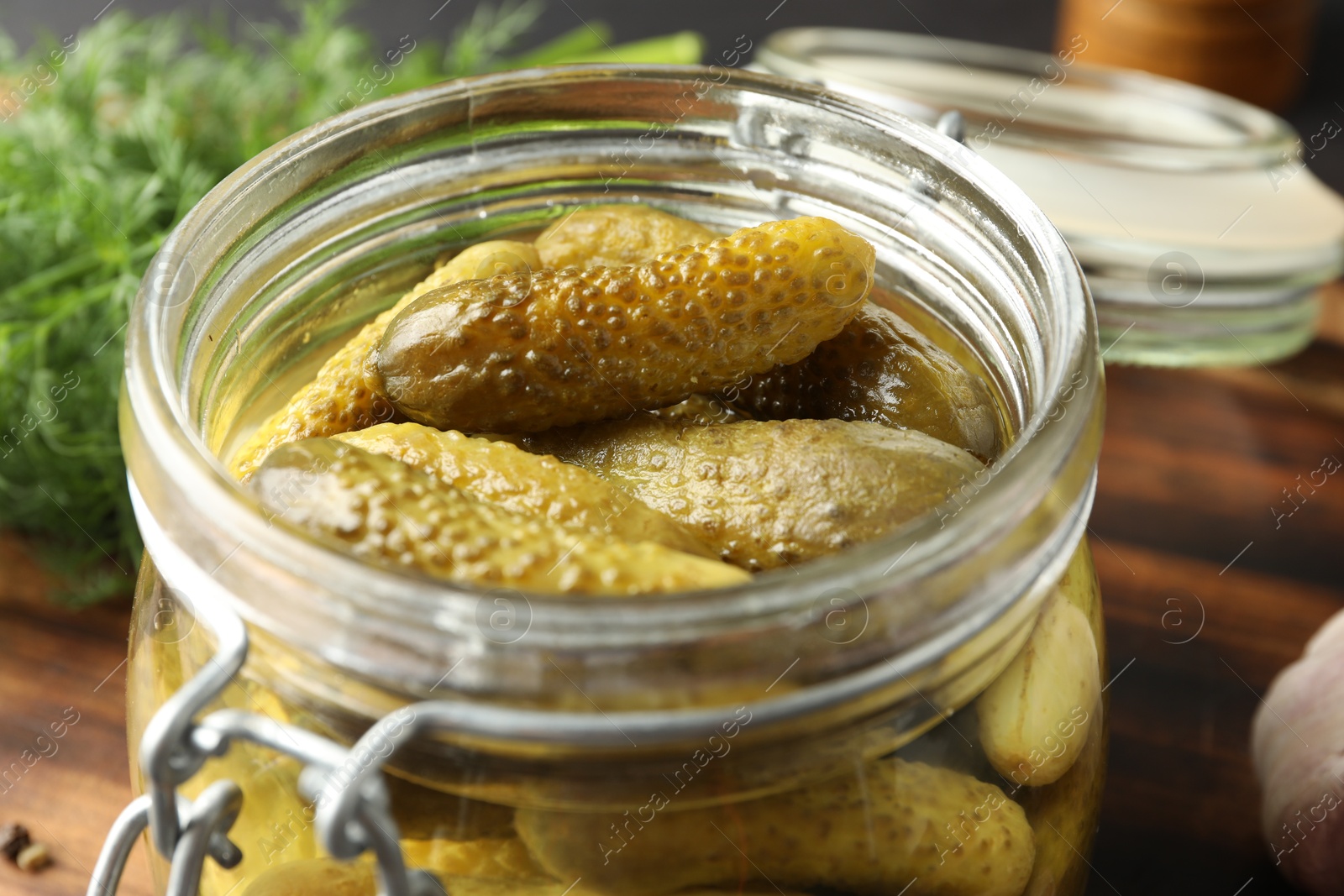 Photo of Pickled cucumbers in jar and dill on wooden table, closeup