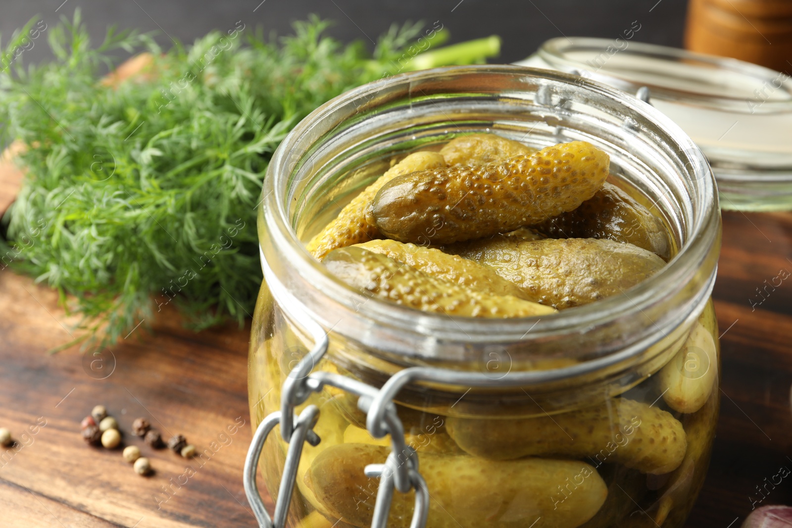 Photo of Pickled cucumbers in jar and dill on wooden table, closeup