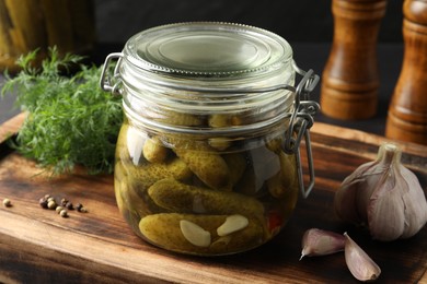 Photo of Pickled cucumbers in jar, garlic and dill on grey wooden table, closeup