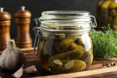 Pickled cucumbers in jar, garlic and dill on grey wooden table, closeup