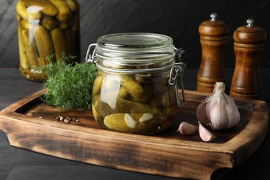 Photo of Pickled cucumbers in jars, garlic and dill on grey wooden table