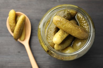 Photo of Jar and spoon with pickled cucumbers on grey wooden table, top view