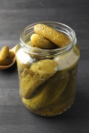 Pickled cucumbers in jar on grey wooden table