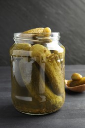 Pickled cucumbers in jar on grey wooden table