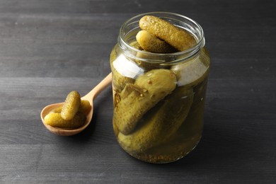 Photo of Jar and spoon with pickled cucumbers on grey wooden table