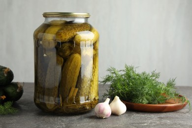 Photo of Pickles in jar, fresh cucumbers, dill and garlic on grey table