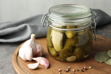 Photo of Pickled cucumbers in jar and spices on grey table