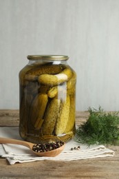 Photo of Pickled cucumbers in jar, dill and peppercorns on wooden table
