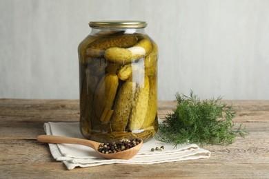 Photo of Pickled cucumbers in jar, dill and peppercorns on wooden table