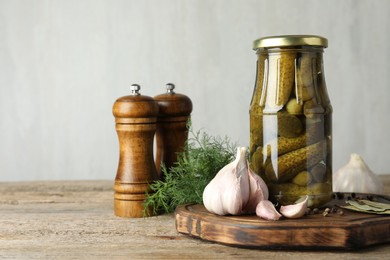 Pickled cucumbers in jar and spices on wooden table. Space for text