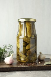 Pickled cucumbers in jar and spices on grey table