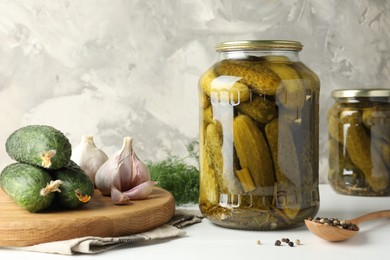 Photo of Pickles in jars, fresh cucumbers and spices on white table