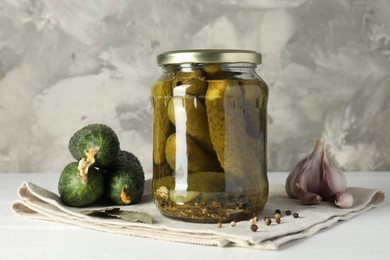 Photo of Pickles in jar, fresh cucumbers and spices on white table