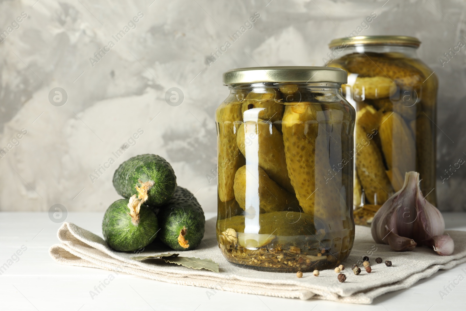 Photo of Pickles in jars, fresh cucumbers and spices on white table