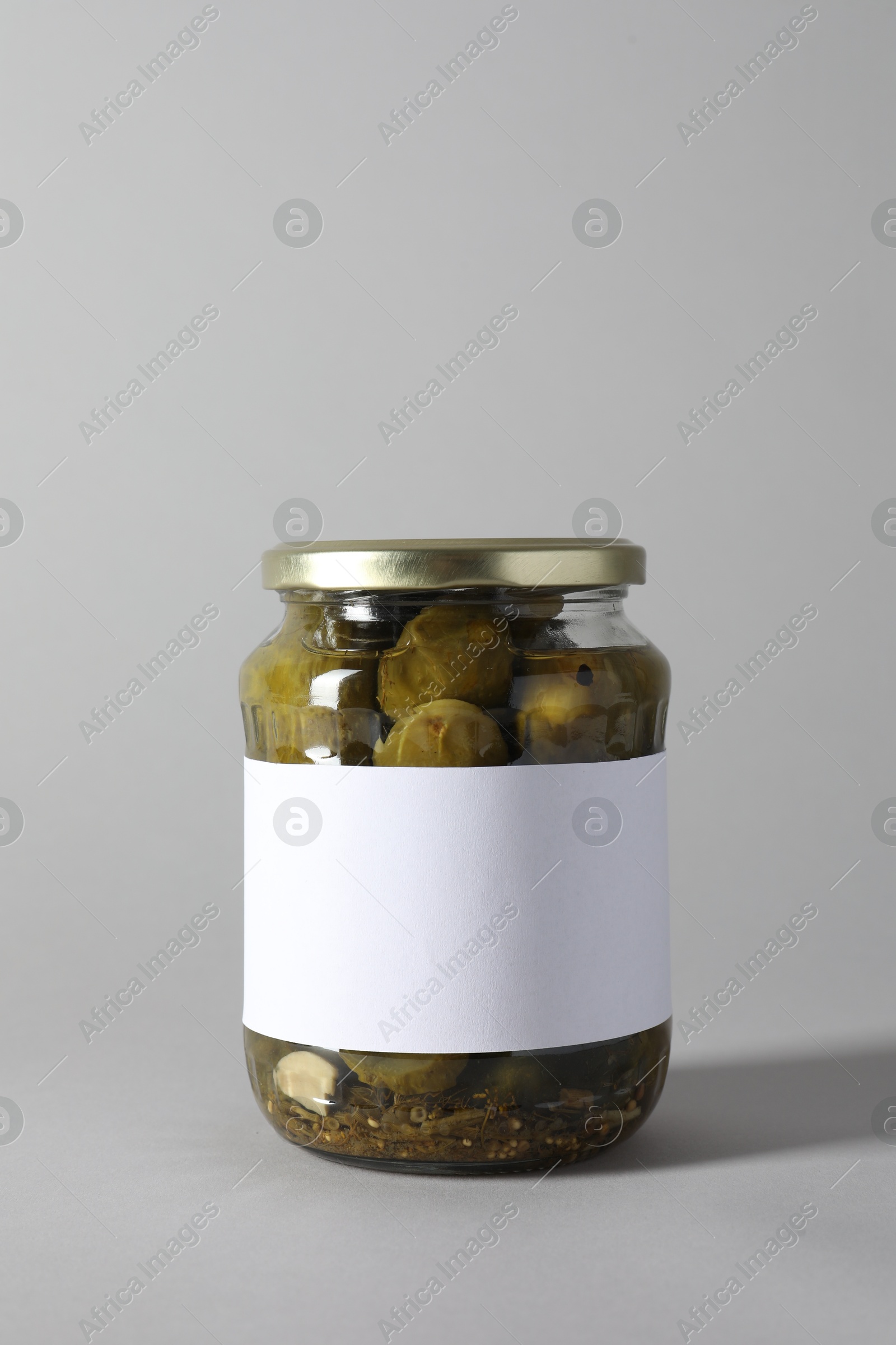 Photo of Pickled cucumbers in jar on light background