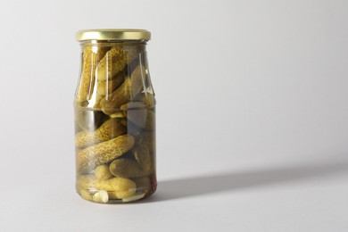 Photo of Pickled cucumbers in jar on light background. Space for text