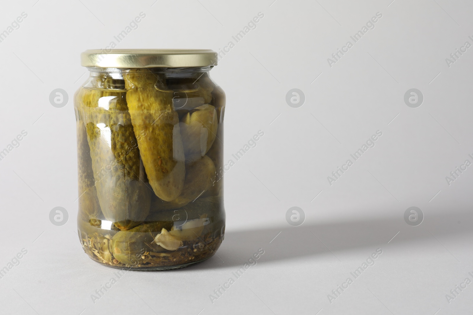 Photo of Pickled cucumbers in jar on light background. Space for text
