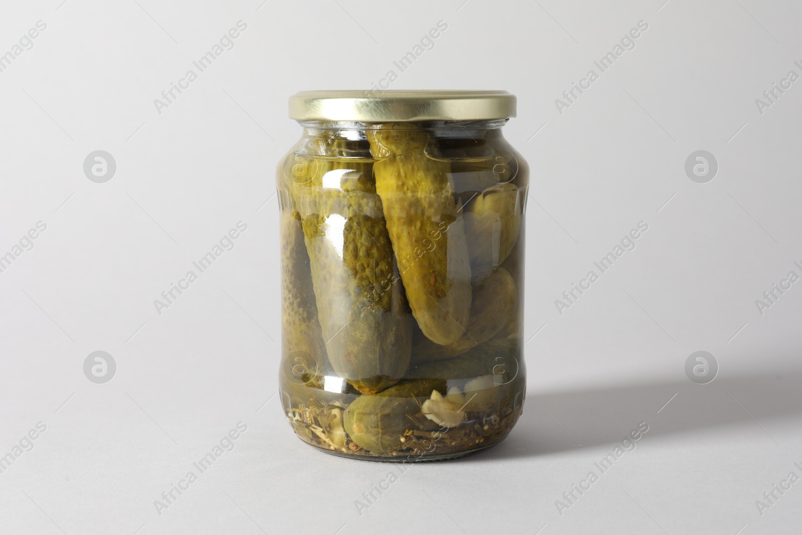 Photo of Pickled cucumbers in jar on light background