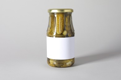 Photo of Pickled cucumbers in jar on light background