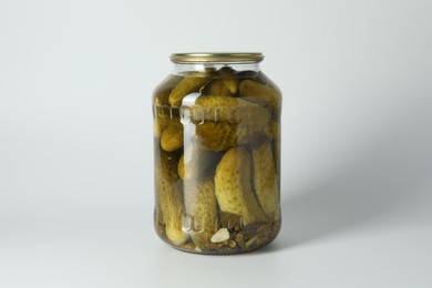 Pickled cucumbers in jar on light background