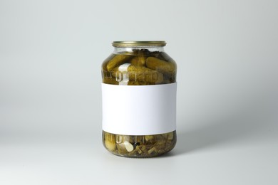 Pickled cucumbers in jar on light background