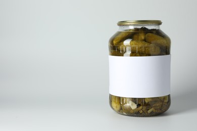 Photo of Pickled cucumbers in jar on light background. Space for text