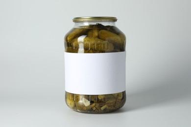 Pickled cucumbers in jar on light background