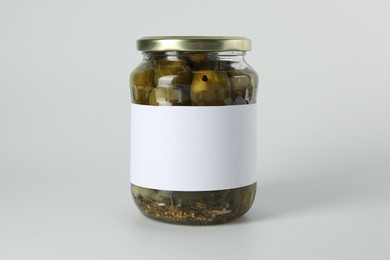 Pickled cucumbers in jar on light background