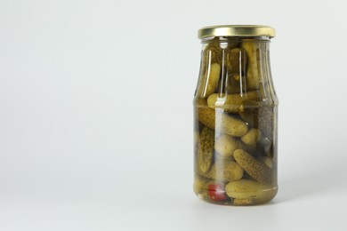 Pickled cucumbers in jar on light background. Space for text